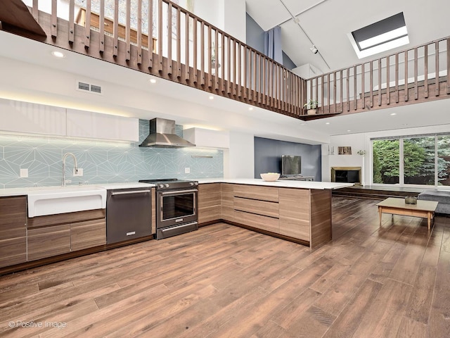 241 E Burlington St Unit A, Riverside, IL 60546 - kitchen featuring appliances with stainless steel finishes, modern cabinets, a sink, wall chimney range hood, and light wood-style floors