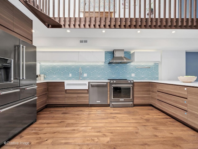 241 E Burlington St Unit A, Riverside, IL 60546 - kitchen featuring wall chimney exhaust hood, stainless steel appliances, modern cabinets, light countertops, and a towering ceiling
