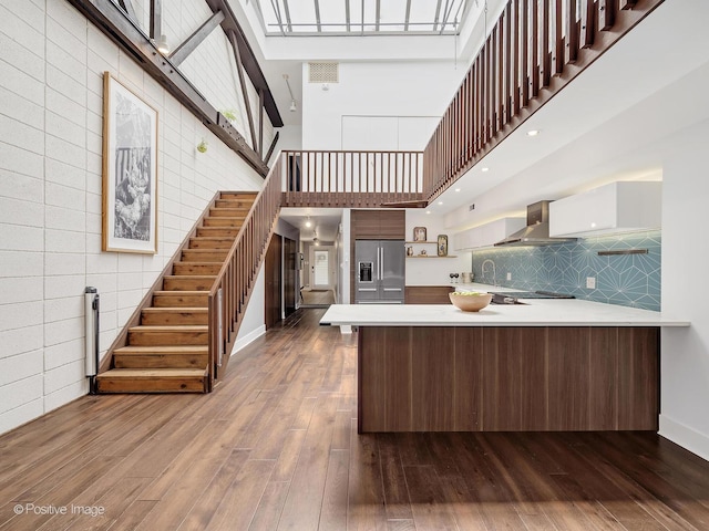 241 E Burlington St Unit A, Riverside, IL 60546 - kitchen featuring open shelves, stainless steel fridge with ice dispenser, wall chimney range hood, a towering ceiling, and a peninsula