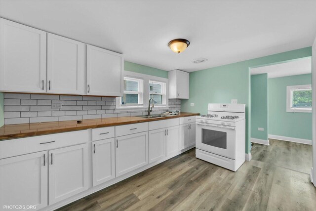 10002 S Torrence Ave, Chicago, IL 60617 - kitchen featuring white gas range, wood counters, a sink, tasteful backsplash, and white cabinetry