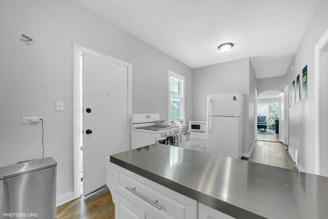 10002 S Torrence Ave, Chicago, IL 60617 - kitchen featuring white appliances, stainless steel countertops, white cabinets, arched walkways, and wood finished floors