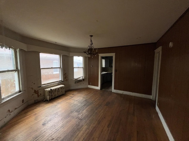 104 Interocean Ave, South Chicago Heights, IL 60411 - unfurnished dining area featuring radiator, a chandelier, hardwood / wood-style floors, wooden walls, and baseboards