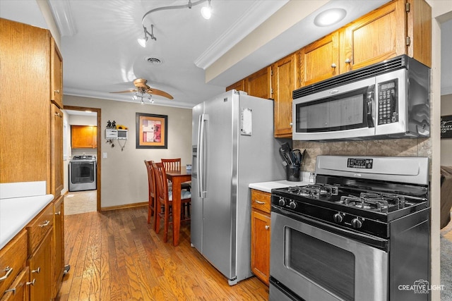 19 Crescent Ct, Montgomery, IL 60538 - kitchen with appliances with stainless steel finishes, ornamental molding, brown cabinets, light countertops, and washer / dryer