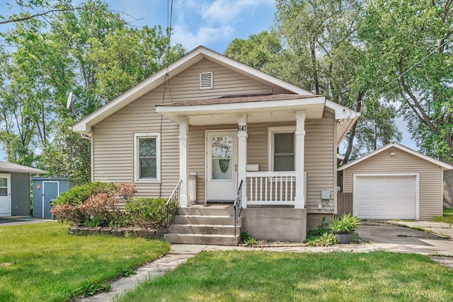 610 W S St, Plano, IL 60545 - view of front of home with an outbuilding, a porch, asphalt driveway, a detached garage, and a front lawn