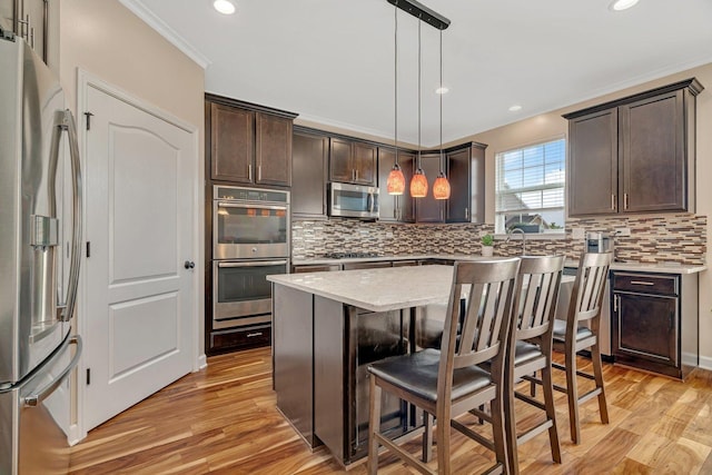 1221 Winding Way, Bolingbrook, IL 60490 - kitchen featuring appliances with stainless steel finishes, dark brown cabinets, light wood-style flooring, tasteful backsplash, and a breakfast bar area