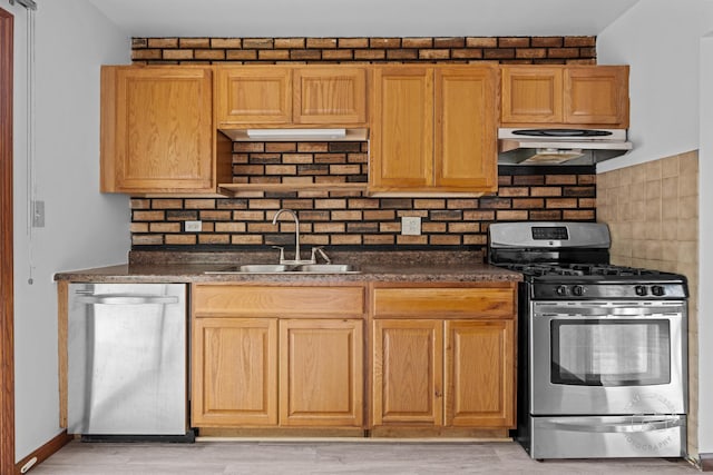 304 Dean Cir, Bolingbrook, IL 60440 - kitchen featuring appliances with stainless steel finishes, under cabinet range hood, dark countertops, decorative backsplash, and light wood-style floors