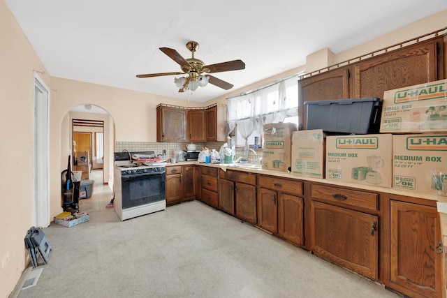 4501 S Kilpatrick Ave, Chicago, IL 60632 - kitchen featuring gas range, arched walkways, ceiling fan, light countertops, and tasteful backsplash