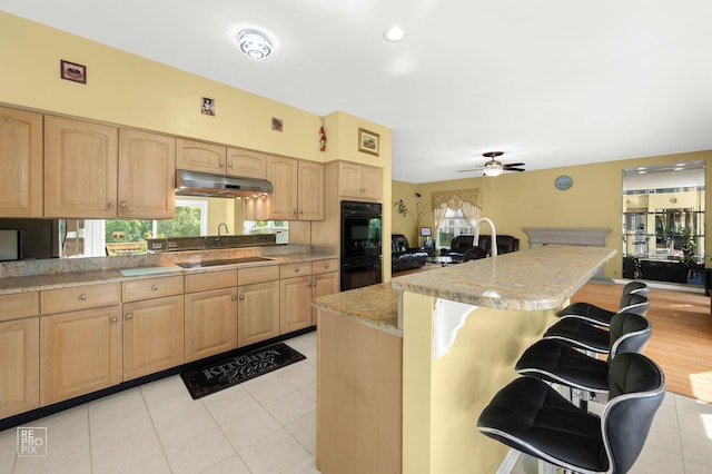 7623 Beringer Ct, Gurnee, IL 60031 - kitchen with black appliances, light brown cabinetry, and a breakfast bar