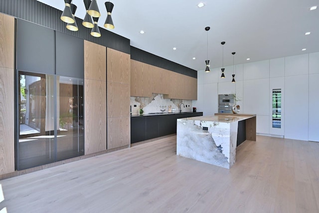 332 W Fremont Ave, Elmhurst, IL 60126 - kitchen with modern cabinets, light wood-style floors, tasteful backsplash, decorative light fixtures, and an island with sink