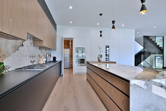 332 W Fremont Ave, Elmhurst, IL 60126 - kitchen with stainless steel appliances, modern cabinets, light wood finished floors, backsplash, and hanging light fixtures