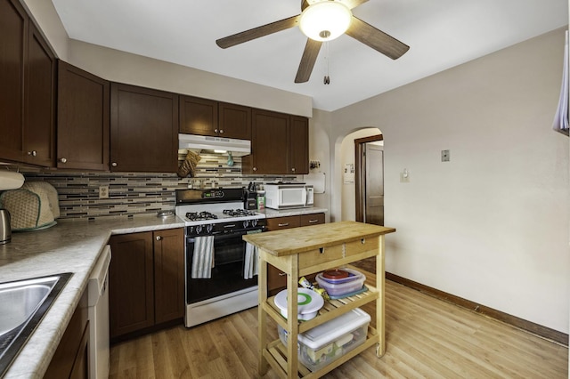 6513 Kane Ave, Hodgkins, IL 60525 - kitchen with gas range, under cabinet range hood, white microwave, arched walkways, and dark brown cabinets