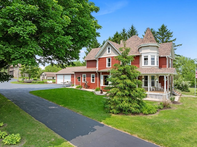 12002 Patterson Rd, Durand, IL 61024 - victorian home featuring asphalt driveway, covered porch, a front lawn, a garage, and a shingled roof