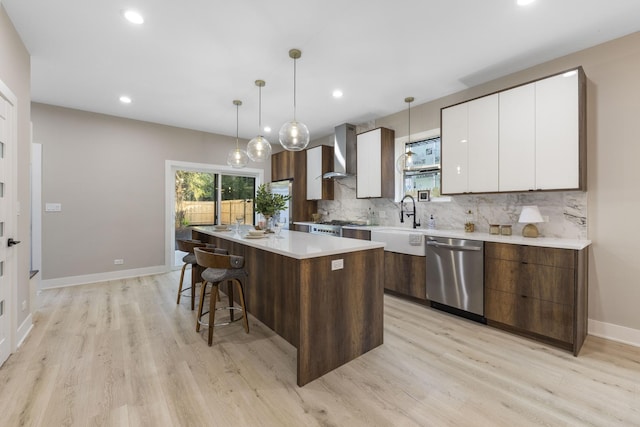 5901 W Erie St, Chicago, IL 60644 - kitchen with stainless steel dishwasher, a kitchen island, wall chimney exhaust hood, light wood-style floors, and white cabinetry