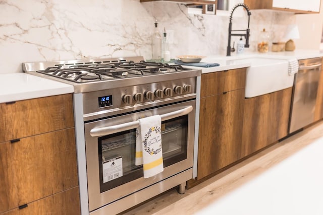 5901 W Erie St, Chicago, IL 60644 - kitchen featuring stainless steel appliances, brown cabinetry, tasteful backsplash, light countertops, and modern cabinets