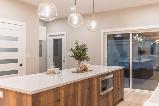 5901 W Erie St, Chicago, IL 60644 - kitchen with modern cabinets, stainless steel microwave, brown cabinets, a spacious island, and light countertops