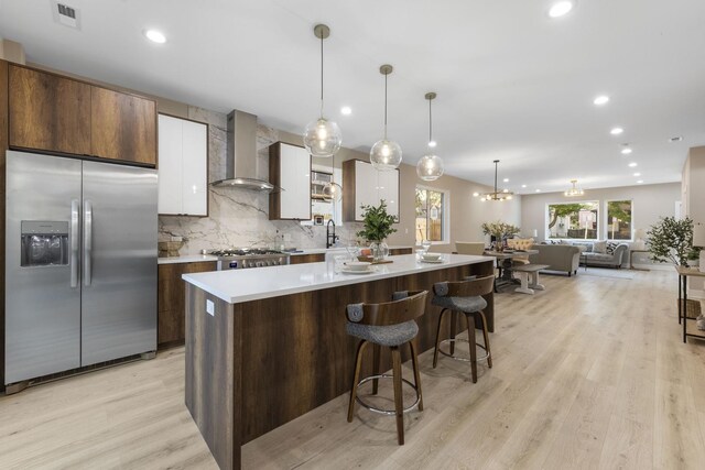 5901 W Erie St, Chicago, IL 60644 - kitchen featuring appliances with stainless steel finishes, wall chimney exhaust hood, a center island, decorative backsplash, and light countertops