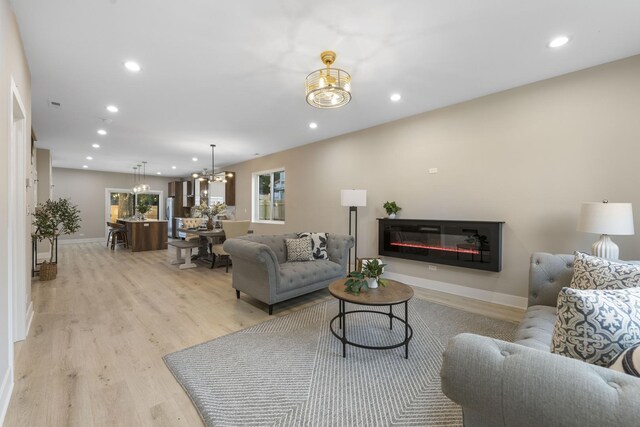 5901 W Erie St, Chicago, IL 60644 - living area featuring light wood finished floors, a glass covered fireplace, a chandelier, recessed lighting, and baseboards