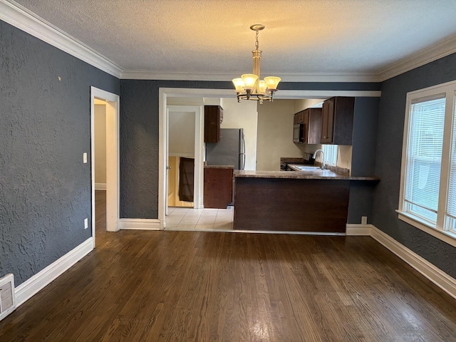 1101 N Ash St, Waukegan, IL 60085 - kitchen featuring appliances with stainless steel finishes, a textured wall, a chandelier, wood finished floors, and dark brown cabinetry