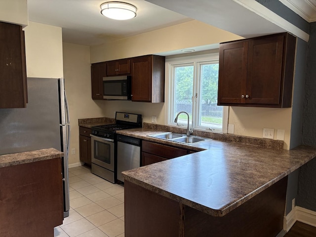 1101 N Ash St, Waukegan, IL 60085 - kitchen with appliances with stainless steel finishes, dark countertops, a peninsula, dark brown cabinets, and light tile patterned flooring
