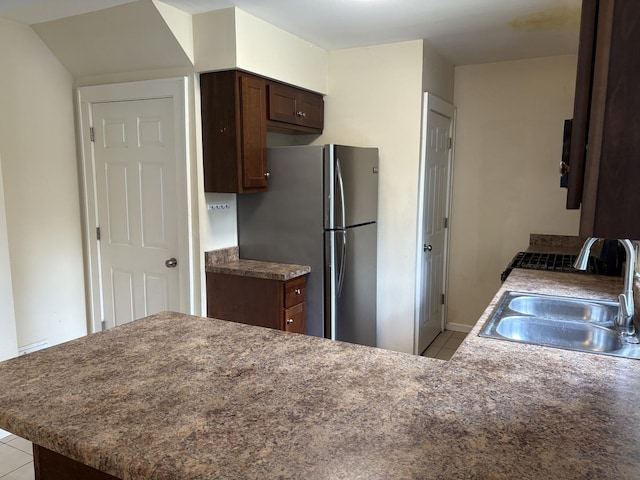 1101 N Ash St, Waukegan, IL 60085 - kitchen featuring light tile patterned floors, freestanding refrigerator, dark brown cabinetry, and a peninsula