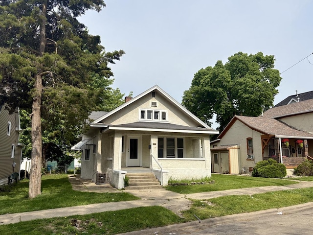 153 N Entrance Ave, Kankakee, IL 60901 - bungalow featuring covered porch, a front lawn, and stucco siding