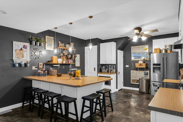 320 E Locust St, Watseka, IL 60970 - kitchen with stainless steel refrigerator with ice dispenser, a peninsula, a breakfast bar, ceiling fan, and white cabinetry