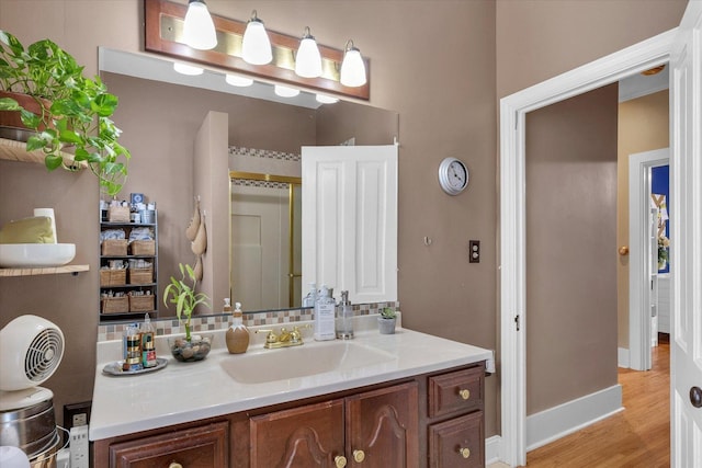 320 E Locust St, Watseka, IL 60970 - full bath featuring vanity, wood finished floors, an enclosed shower, and decorative backsplash