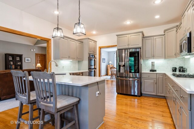 8820 Wilcox Ct, Newark, IL 60541 - kitchen with stainless steel appliances, gray cabinets, a kitchen breakfast bar, tasteful backsplash, and light wood-style floors