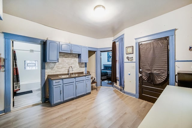 1340 E 76th St, Chicago, IL 60619 - kitchen with light wood-style flooring, a sink, backsplash, and dark countertops