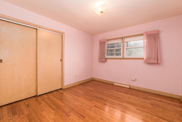 8560 W Winona St, Chicago, IL 60656 - unfurnished bedroom with wood finished floors, a closet, and a baseboard heating unit