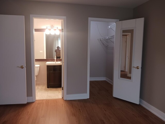 366 Pinetree Ln Unit B1, Schaumburg, IL 60193 - unfurnished bedroom with a walk in closet, a sink, a closet, light wood finished floors, and baseboards