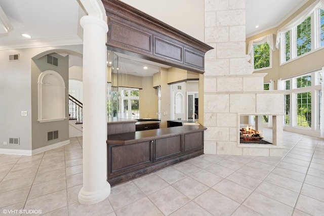 29026 N Brassie Ct, Ivanhoe, IL 60060 - kitchen with ornamental molding, light tile patterned flooring, healthy amount of natural light, dark brown cabinets, and a multi sided fireplace