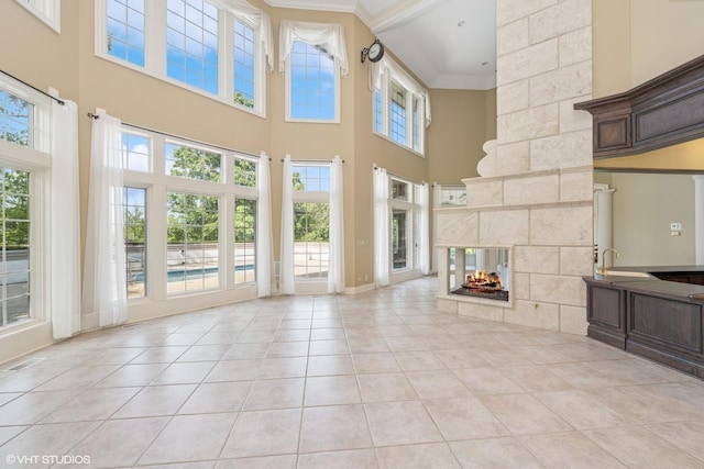 29026 N Brassie Ct, Ivanhoe, IL 60060 - unfurnished living room featuring a sink, light tile patterned floors, a multi sided fireplace, a towering ceiling, and ornamental molding