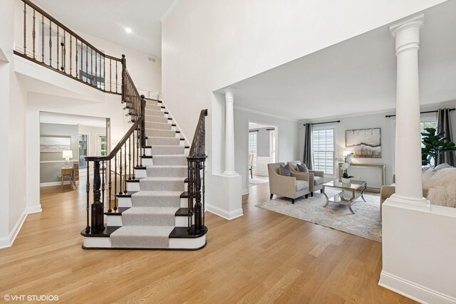 6724 Greene Rd, Woodridge, IL 60517 - stairway featuring ornate columns, wood finished floors, baseboards, crown molding, and a high ceiling