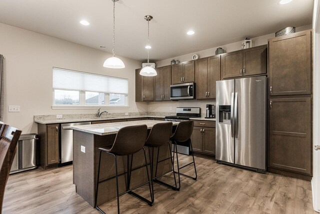 1125 Juniper Dr, Sycamore, IL 60178 - kitchen featuring stainless steel appliances, dark brown cabinetry, a kitchen island, a breakfast bar area, and light wood-type flooring