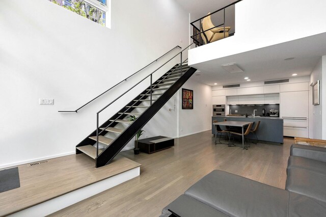 839 N Hermitage Ave Unit 101, Chicago, IL 60622 - living room featuring stairs, wood finished floors, a towering ceiling, baseboards, and recessed lighting
