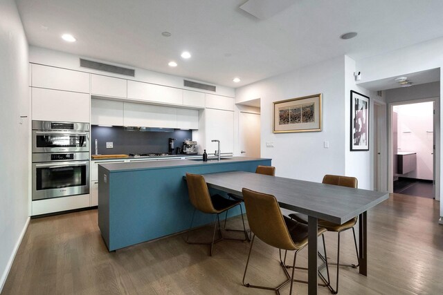 839 N Hermitage Ave Unit 101, Chicago, IL 60622 - kitchen with double oven, modern cabinets, dark wood-style floors, white cabinets, and recessed lighting