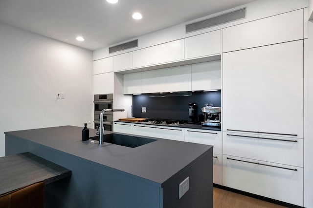 839 N Hermitage Ave Unit 101, Chicago, IL 60622 - kitchen with modern cabinets, white cabinetry, a sink, dark countertops, and recessed lighting
