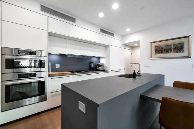 839 N Hermitage Ave Unit 101, Chicago, IL 60622 - kitchen featuring a sink, stainless steel double oven, white cabinets, and recessed lighting