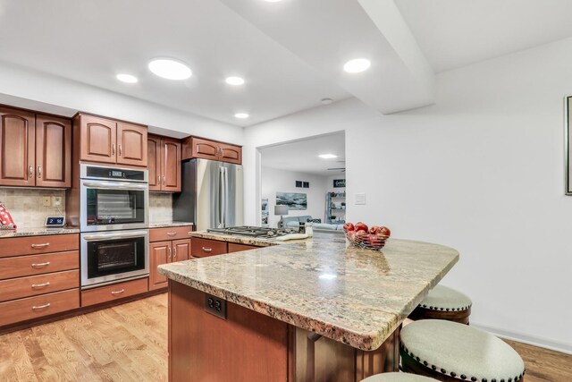 2310 Malik Ct, Glenview, IL 60025 - kitchen featuring stainless steel appliances, a kitchen bar, backsplash, light wood-style flooring, and light stone countertops