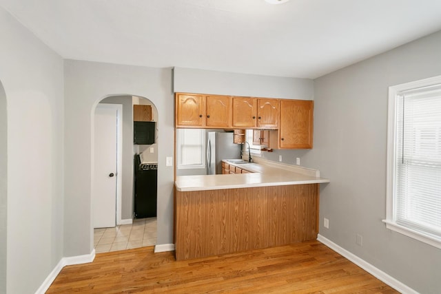3256 186th St, Lansing, IL 60438 - kitchen featuring arched walkways, light countertops, light wood finished floors, and freestanding refrigerator