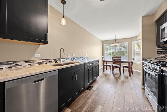 2312 Scott Ln Unit 2312, Aurora, IL 60502 - kitchen with appliances with stainless steel finishes, decorative backsplash, dark cabinetry, wood finished floors, and hanging light fixtures