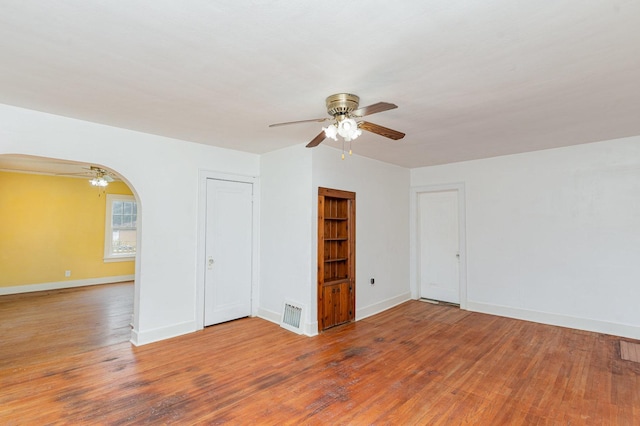 1018 Jericho Rd, Aurora, IL 60506 - empty room with a ceiling fan, wood finished floors, arched walkways, and baseboards