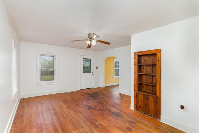 1018 Jericho Rd, Aurora, IL 60506 - empty room with arched walkways, ceiling fan, baseboards, and wood finished floors