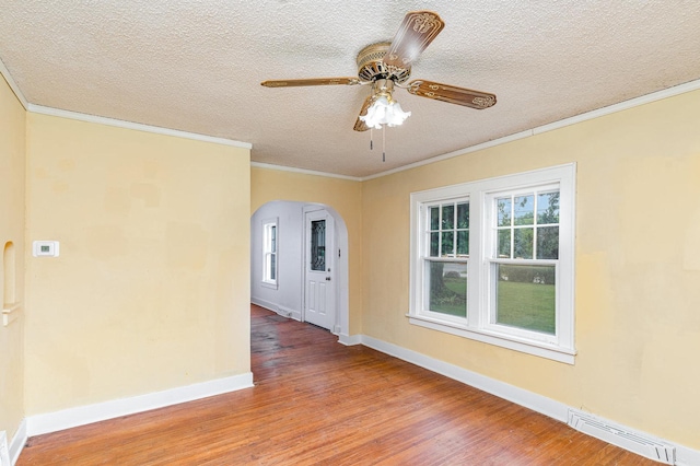 1018 Jericho Rd, Aurora, IL 60506 - spare room with arched walkways, wood finished floors, ornamental molding, a textured ceiling, and baseboards