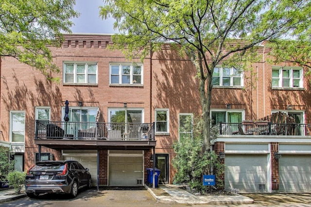 2801 N Wolcott Ave Unit L, Chicago, IL 60657 - back of house featuring brick siding, an attached garage, a balcony, and driveway
