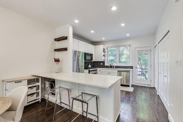2801 N Wolcott Ave Unit L, Chicago, IL 60657 - kitchen with stainless steel appliances, a peninsula, white cabinets, dark wood-style floors, and recessed lighting
