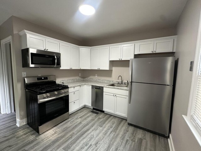 490 Country Club Dr, Kankakee, IL 60901 - kitchen featuring stainless steel appliances, a sink, light wood-style flooring, white cabinets, and light countertops