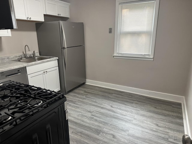 490 Country Club Dr, Kankakee, IL 60901 - kitchen featuring appliances with stainless steel finishes, white cabinets, a sink, baseboards, and light wood-type flooring