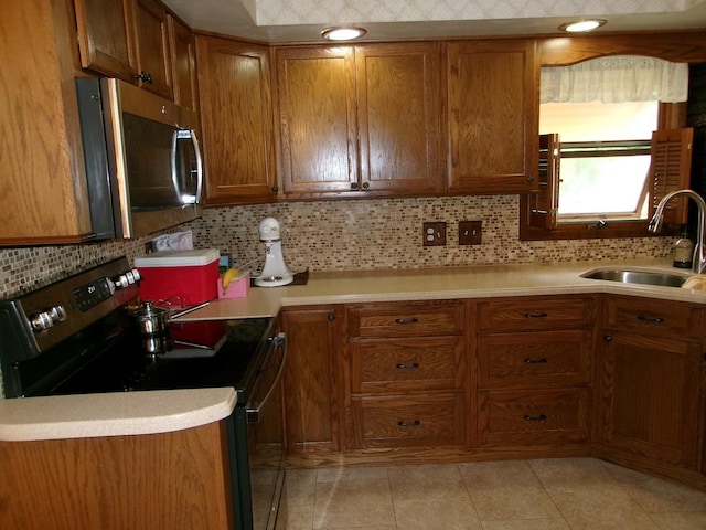 1425 Peoria St, Peru, IL 61354 - kitchen featuring stainless steel microwave, electric range, a sink, brown cabinets, and decorative backsplash